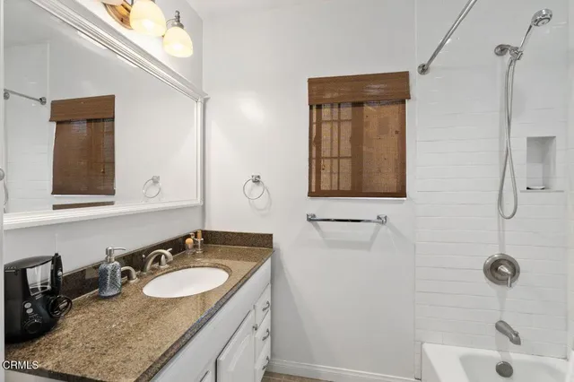 a bathroom with a granite countertop sink and a mirror