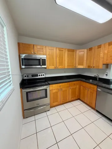 a kitchen with granite countertop a stove a sink and a microwave