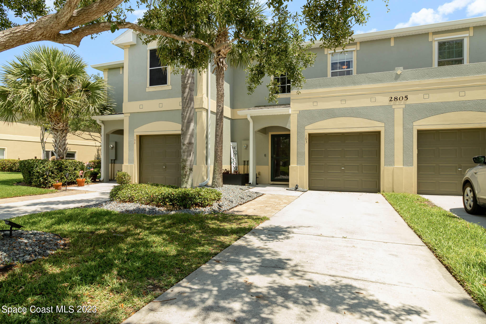 2805 Reston Street, Unit 103 Melbourne, FL 32935 - Photo 1 of 36 a view of a white house with a small yard plants and a large tree
