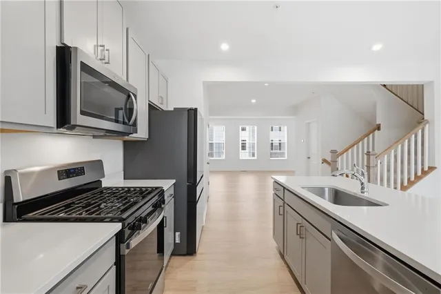 a kitchen with stainless steel appliances granite countertop a sink a stove and a wooden floors