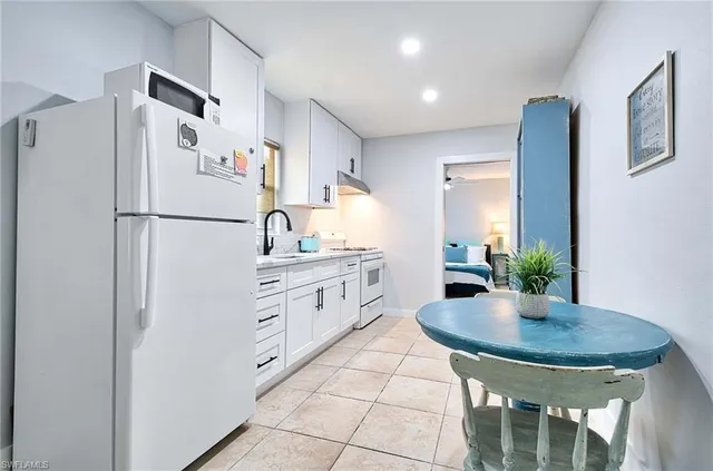 a kitchen with stainless steel appliances a refrigerator a sink a table and chairs