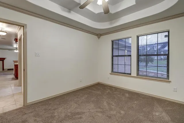 an empty room with windows and chandelier fan