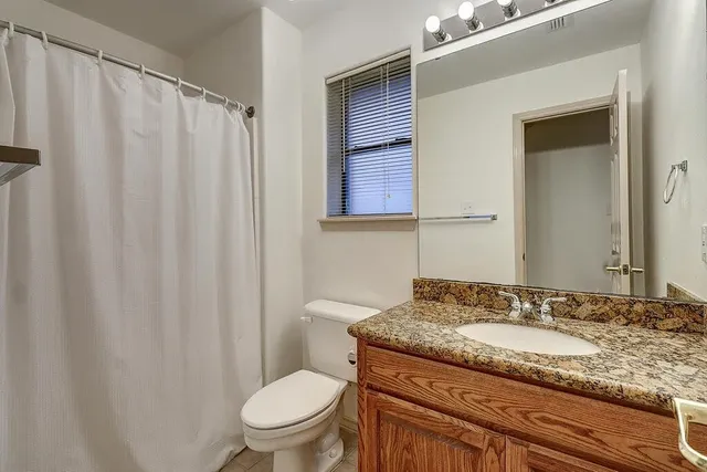 a bathroom with a granite countertop sink toilet and a mirror