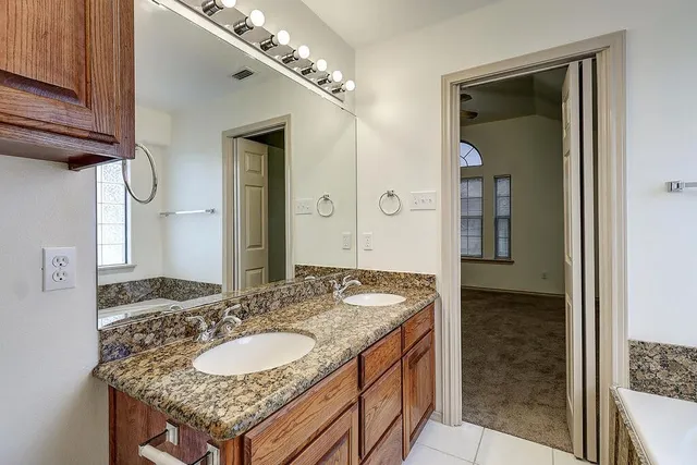 a bathroom with a granite countertop double vanity and a mirror
