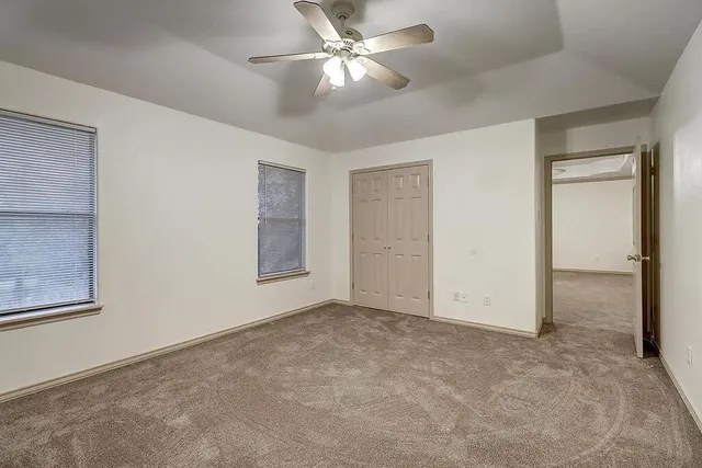 an empty room with closet and a ceiling fan