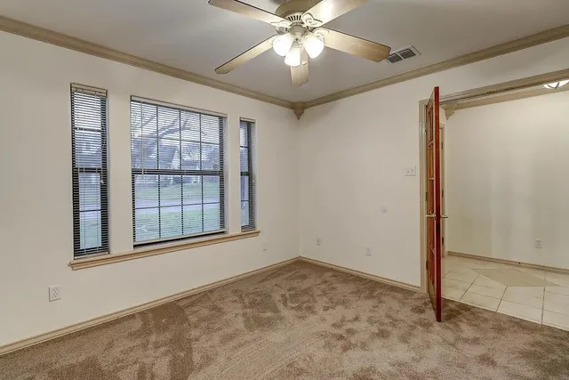 an empty room with windows and fan