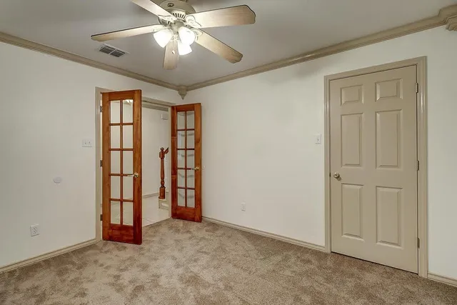 an empty room with chandelier fan and windows