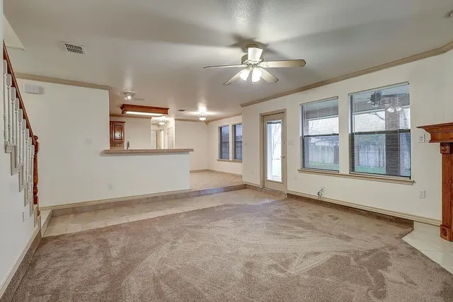 a view of an empty room with chandelier fan and wooden floor