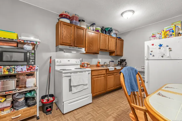 a kitchen with stainless steel appliances granite countertop a sink dishwasher and a refrigerator with wooden floor