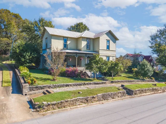 a view of a house with a big yard plants and large trees