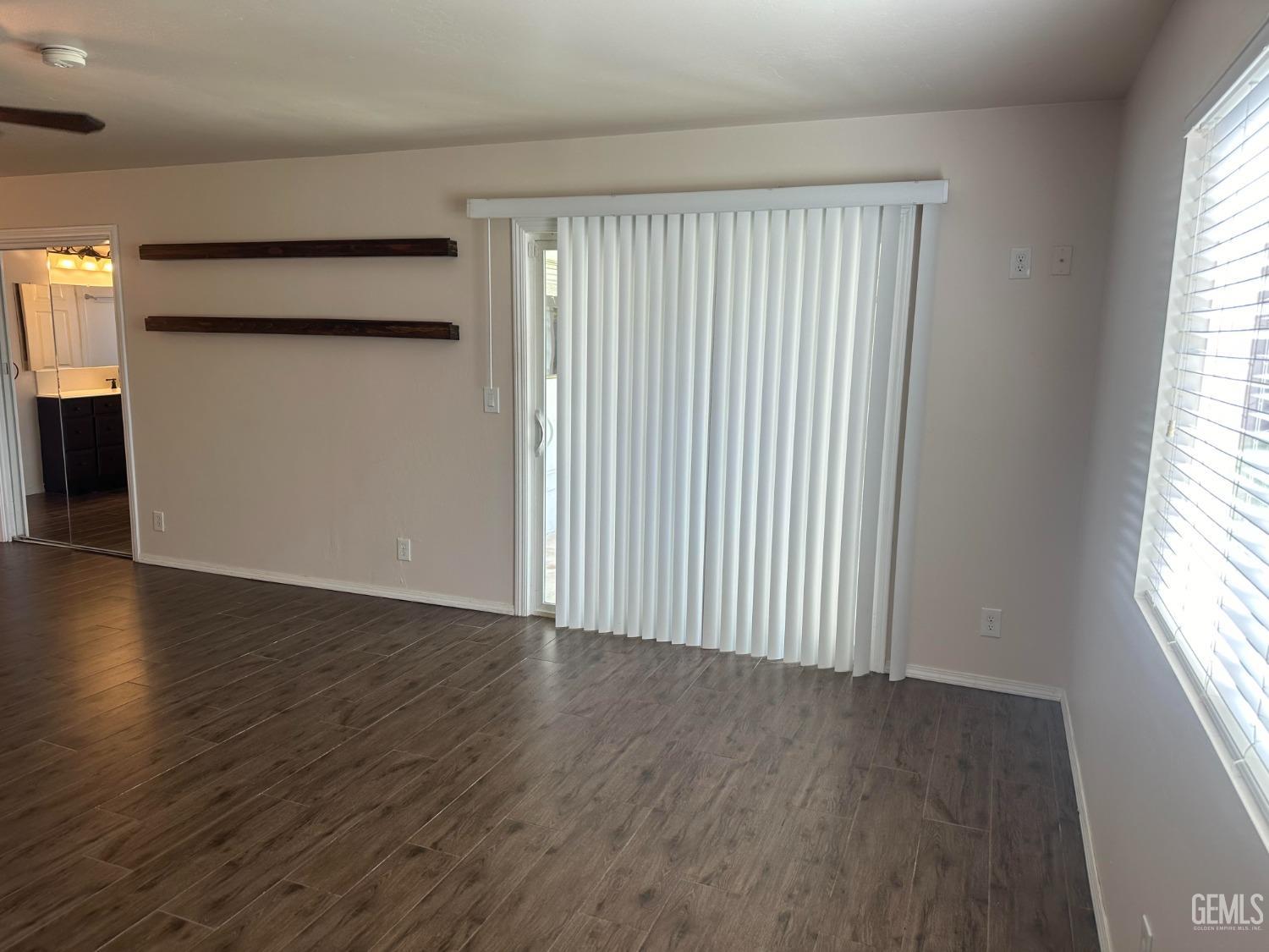 Undisclosed Address Bakersfield, CA 93306 - Photo 12 of 27 an empty room with wooden floor and windows with curtains