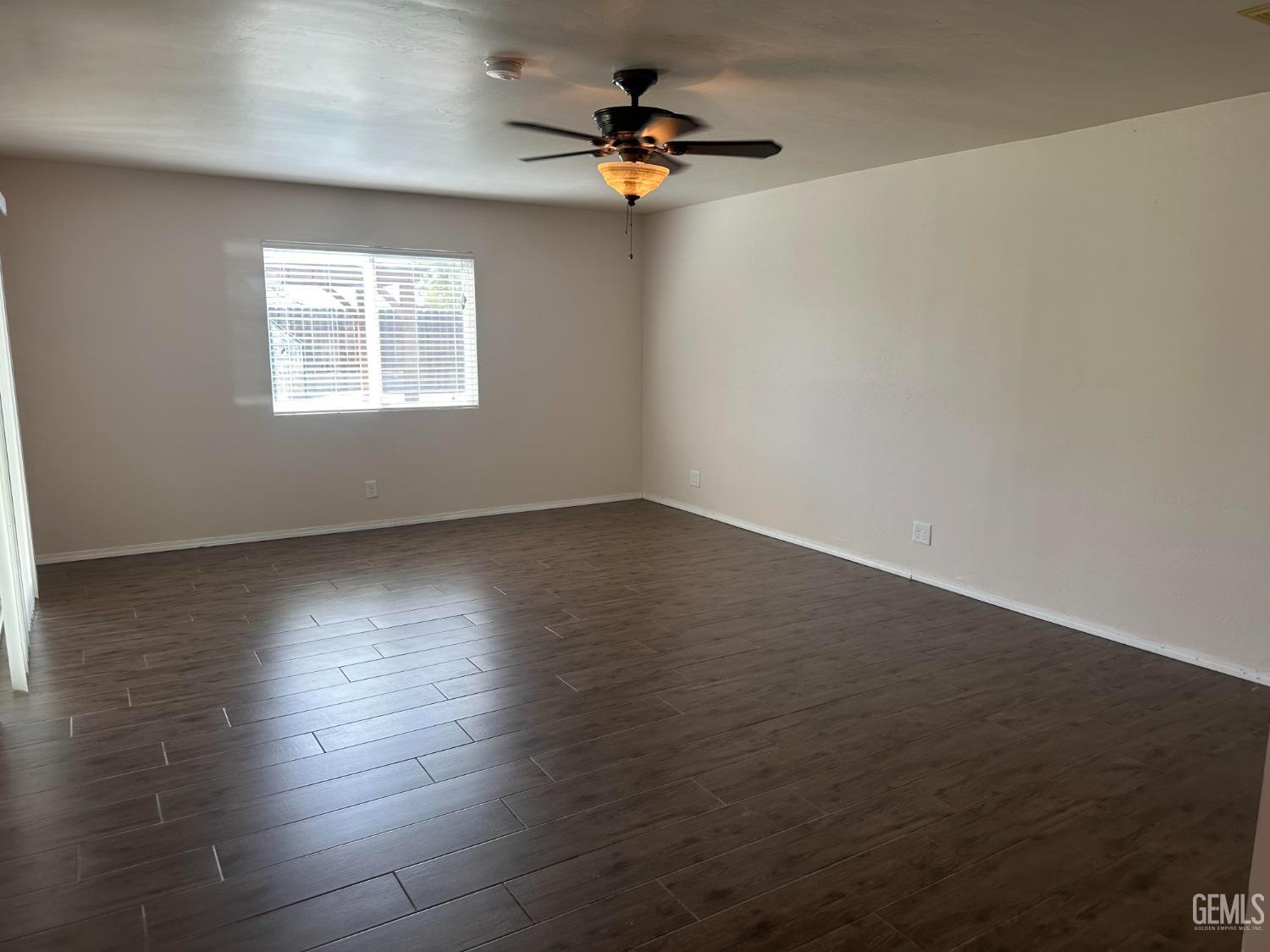Undisclosed Address Bakersfield, CA 93306 - Photo 9 of 27 an empty room with wooden floor chandelier fan and windows