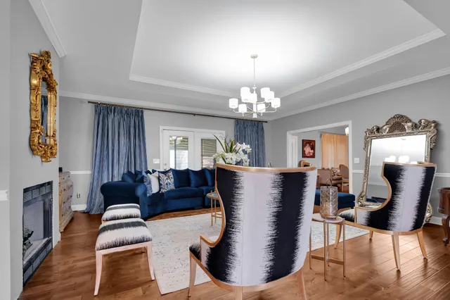 a living room with furniture a chandelier a fireplace and wooden floor