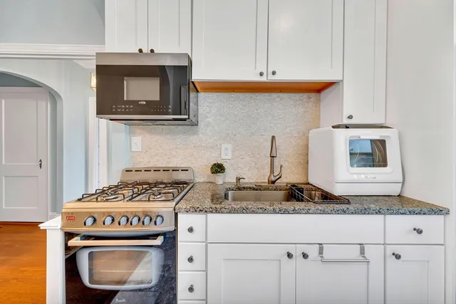 a kitchen with granite countertop a sink a stove and cabinets