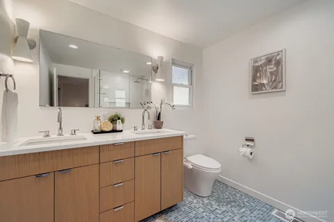 a bathroom with a toilet a sink a mirror and a window