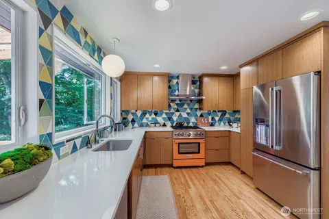 a kitchen with stainless steel appliances granite countertop a refrigerator a oven a sink with wooden floors and cabinets