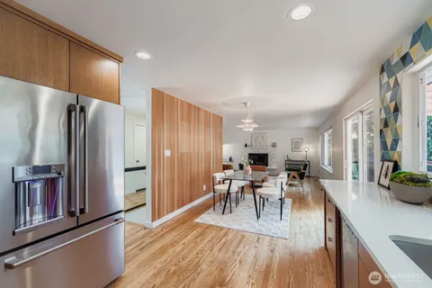 a kitchen with stainless steel appliances a dining table chairs and wooden floor