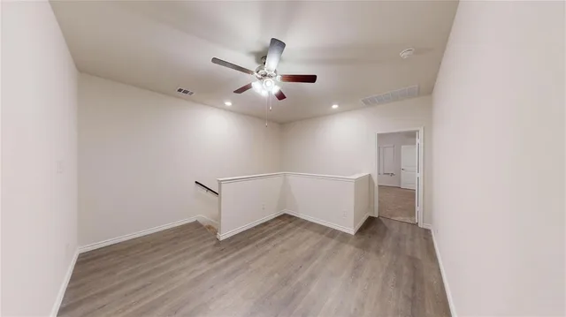a view of a room with wooden floor and ceiling fan