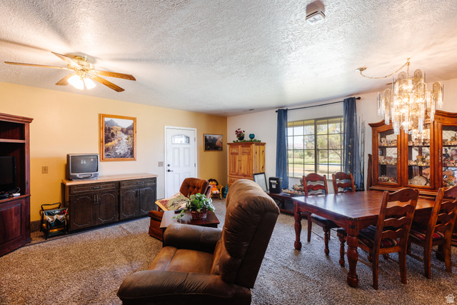 1470 Redwood Tree Street St. George, UT 84790 - Photo 23 of 53 Open concept living and dining area featuring a textured ceiling, neutral carpeting, and a large picture window with outdoor scenery
