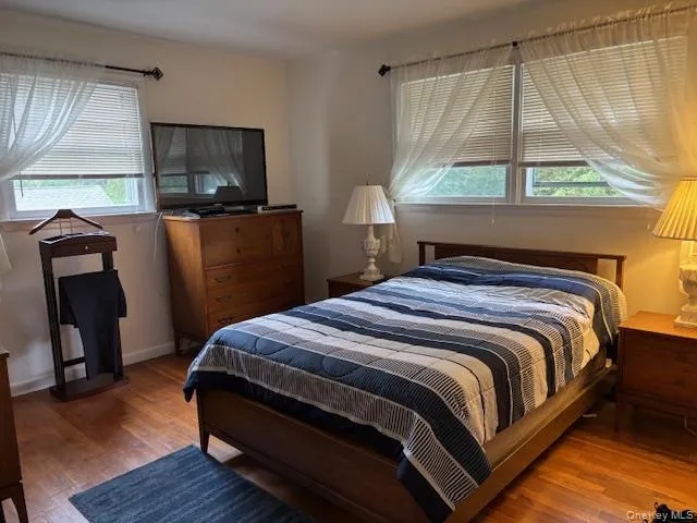 a bedroom with a bed a flat screen tv and a window