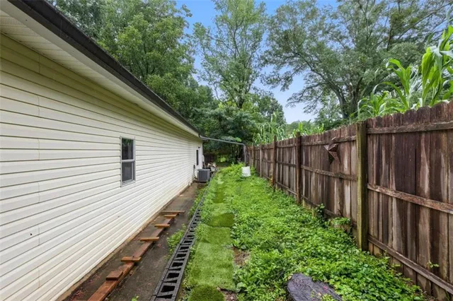 a view of a backyard with wooden fence and large trees