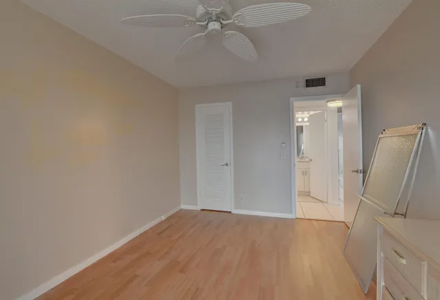 a view of empty room with wooden floor and fan