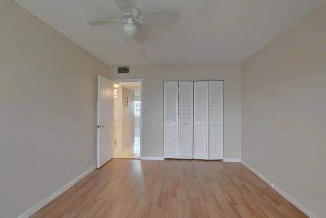 an empty room with wooden floor and fan