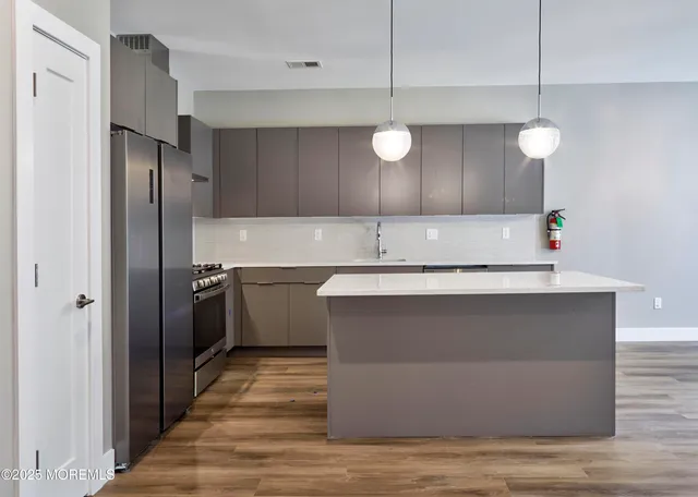 a kitchen with kitchen island a counter top space cabinets and stainless steel appliances