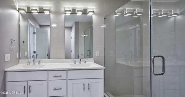 a bathroom with a double vanity sink mirror and shower