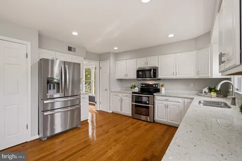 a kitchen with stainless steel appliances granite countertop a refrigerator and a stove top oven