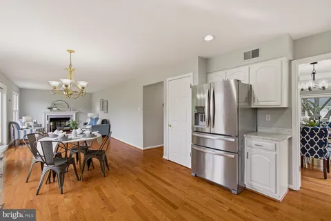 a kitchen with stainless steel appliances a dining table chairs stove refrigerator and cabinets