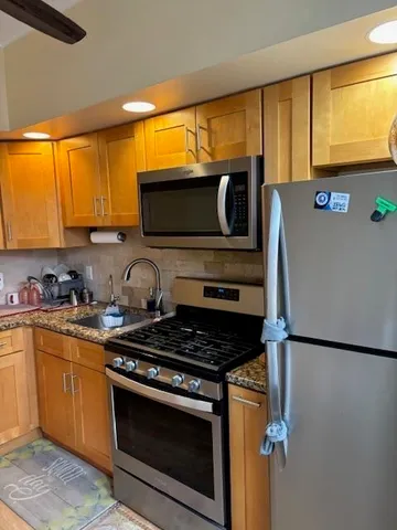 a kitchen with stainless steel appliances granite countertop a stove a sink and a microwave