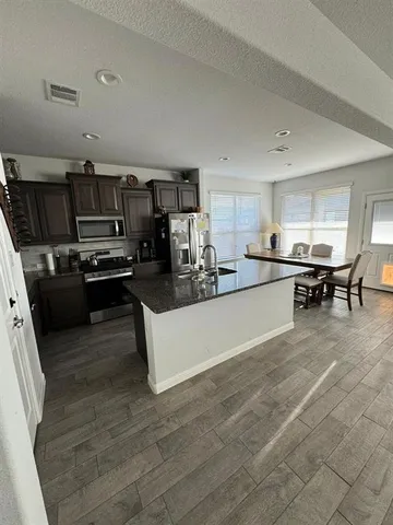 a kitchen with stainless steel appliances a stove a sink a microwave a refrigerator and cabinets