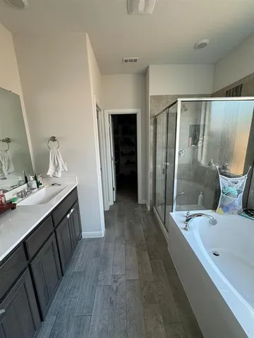 a bathroom with a double vanity sink a large mirror and a bathtub