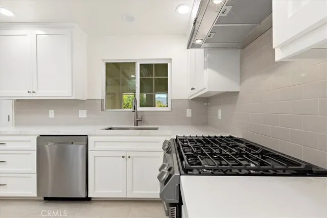 a kitchen with white cabinets and a stove top oven