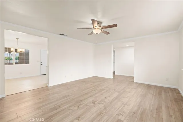 a view of empty room with wooden floor and ceiling fan