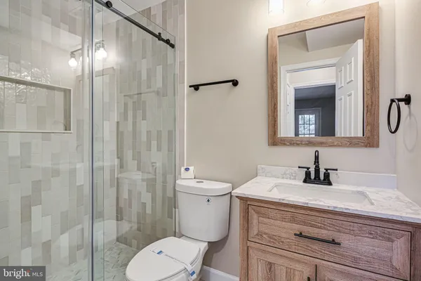 a bathroom with a granite countertop sink toilet a mirror and shower