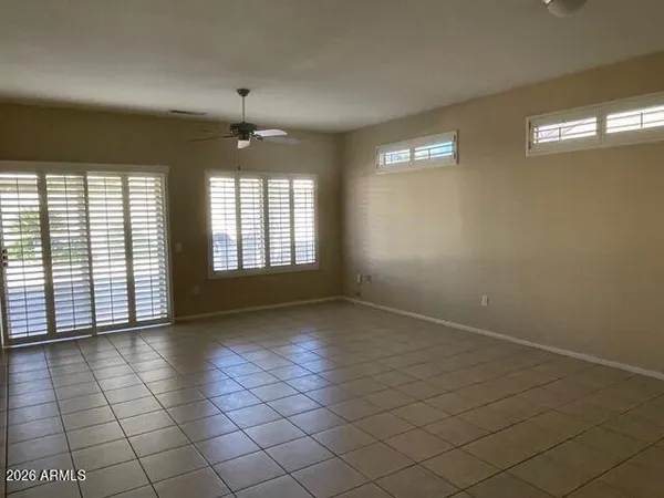 an empty room with windows and ceiling fan