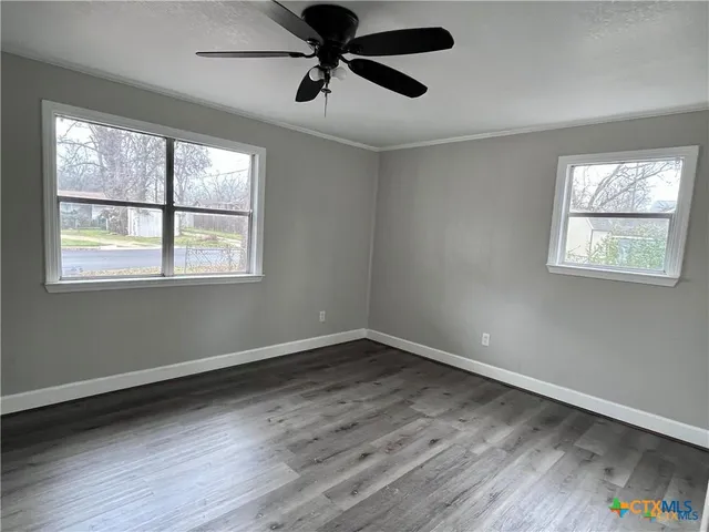 a view of an empty room with wooden floor and a window