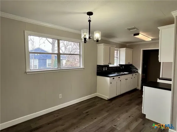 a kitchen with granite countertop a stove cabinets and wooden floor