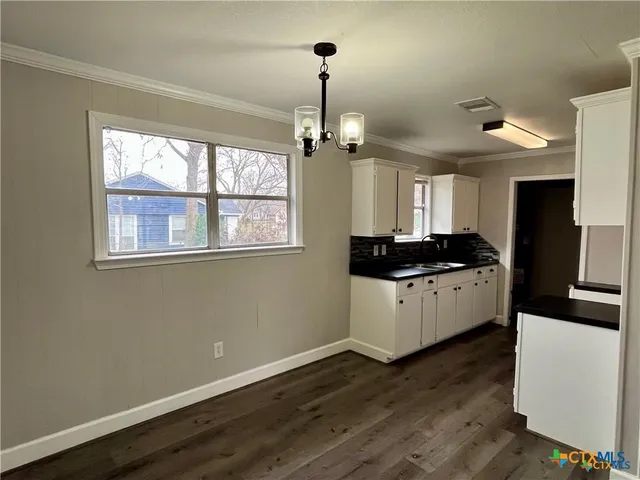 a kitchen with granite countertop a stove cabinets and wooden floor