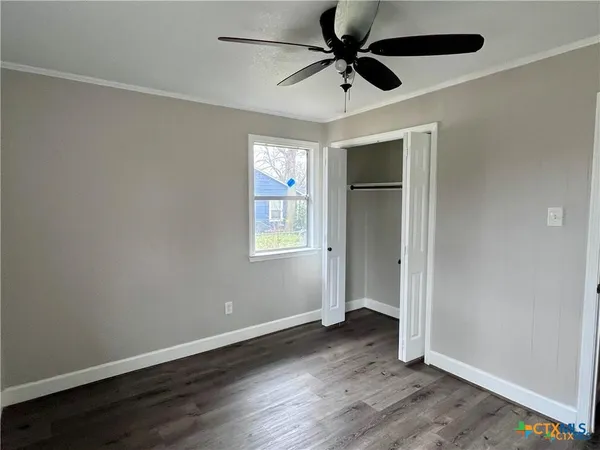 an empty room with wooden floor fan and windows
