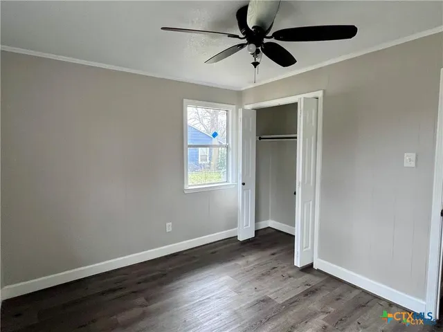 an empty room with wooden floor fan and windows