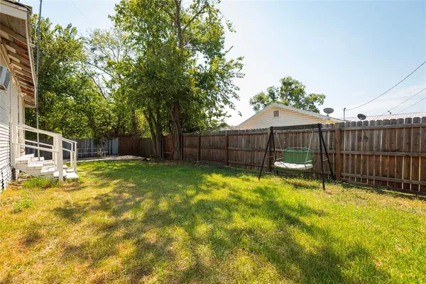 a view of a backyard with a small plants and wooden fence