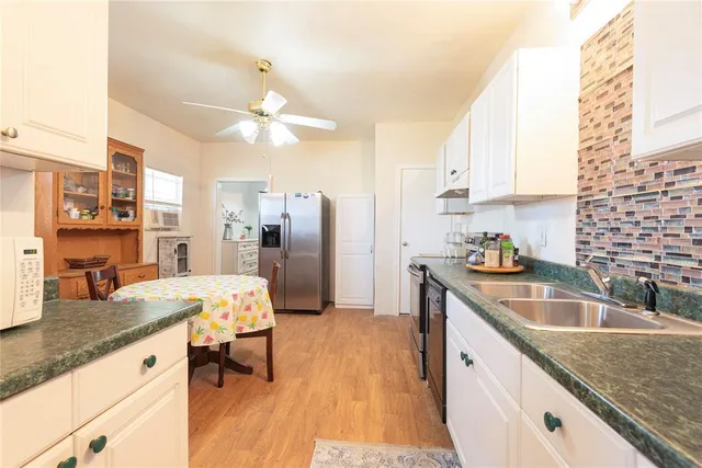 a kitchen with granite countertop a sink refrigerator and microwave