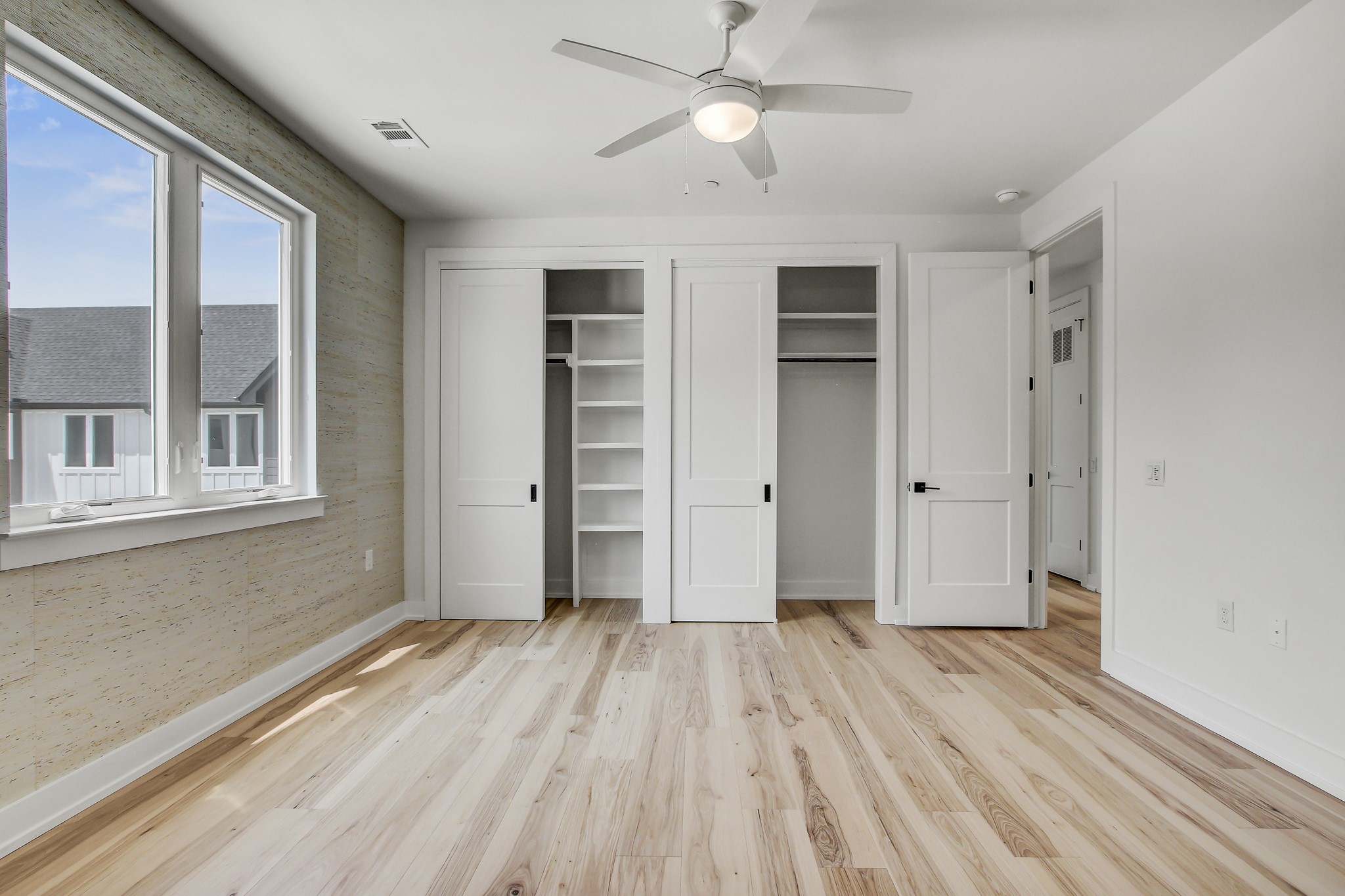 4127 East 12th Street, Unit 4 Austin, TX 78721 - Photo 16 of 32 Unfurnished bedroom with baseboards, light wood-style floors, multiple closets, and a ceiling fan