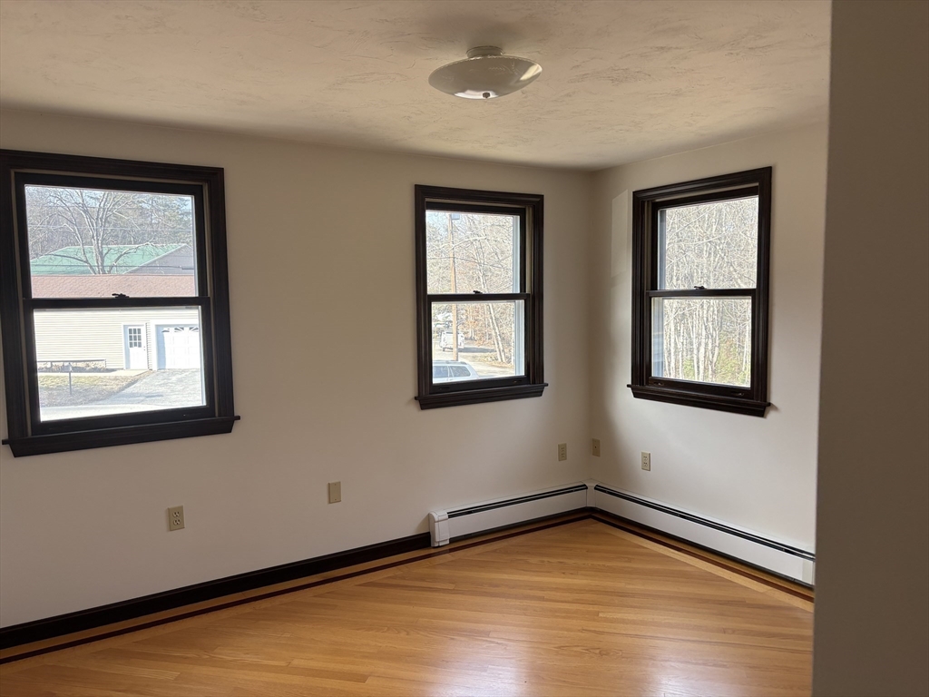94 Monroe Street, Unit 2 Douglas, MA 01516 - Photo 8 of 10 a view of an empty room with wooden floor and a window