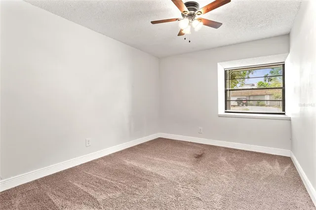 an empty room with a window and a fan