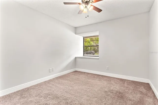 an empty room with a window and a fan
