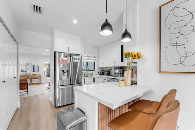 a kitchen with stainless steel appliances a refrigerator a stove a sink and a dining table with wooden floor